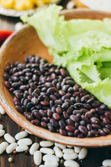 Black beans on brown pottery plate over wooden board.