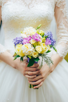 beautiful wedding bouquet in the delicate hands of the bride in a white dress