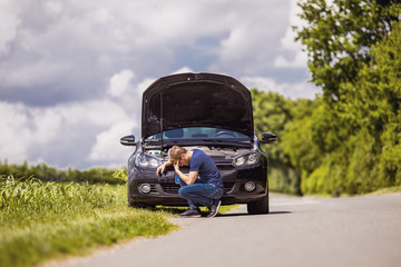 despaired man in front of his car which have a breakdown in the rural nature