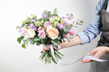 beautiful bouquet made of different flowers in young girl hand . colorful color mix flower. Work clothing in a blue shirt and gray apron