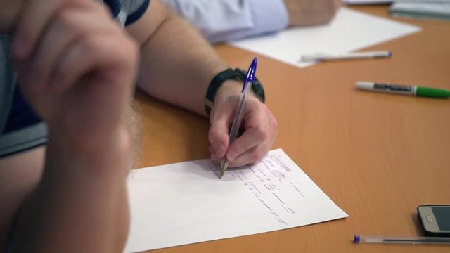 The left-handed man writes on paper