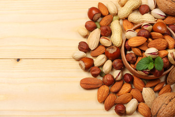 mix almonds, cashew nuts, hazelnut, peanuts, walnuts, pistachio on wooden background. Top view with copy space
