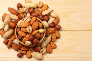 mix almonds, cashew nuts, hazelnut, peanuts, walnuts, pistachio on wooden background. Top view with copy space