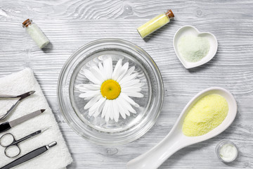 hands care set for manicure with chamomile on gray wooden background top view