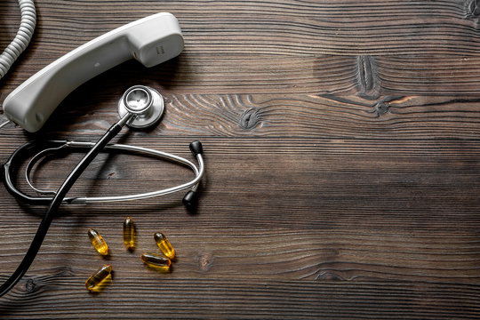 Phone Handset, Pills And Phonendoscope On Dark Wooden Desk Top View Make Appointment With A Doctor Space For Text