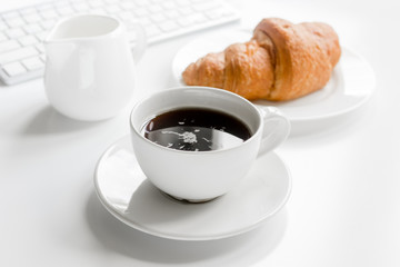 Office lunch with coffee and croissant, keyboard on white table background