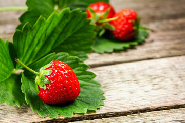 photo of delicious strawberries on wooden table in front of brown rustic background