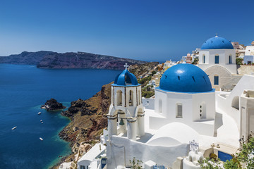 Fototapeta premium Kościoły z niebieskimi kopułami w miejscowości Oia, Santorini (Thira), Cyklady, Morze Egejskie, Grecja