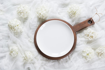 Elegance white plate with floral decor on white wooden board. Rustic stile. Top view.