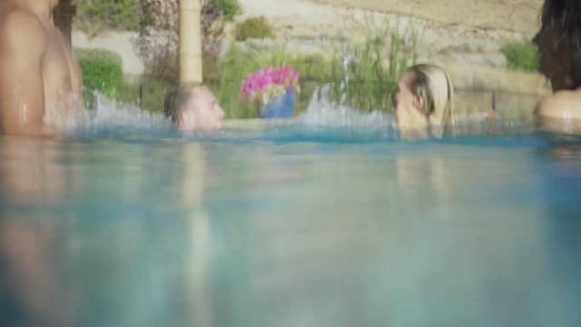 Medium slow motion shot of friends splashing in swimming pool. Cedar Hills, Utah, United States
