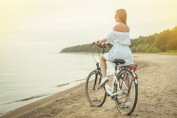 Fototapeta premium Summer. Beautiful woman with bike on the beach