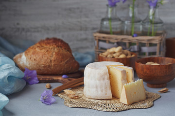 A head of fresh organic cheese served with bread, nuts, white wine and summer flowers.