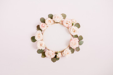 Embroidery frame with beige rose flower buds isolated on pale pastel pink background. Flat lay, top...