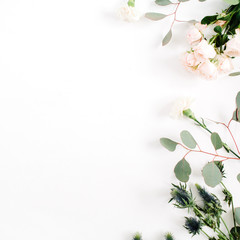 Fototapeta premium Beżowy róża kwiaty, kwiat eringium, gałęzie eukaliptusa na białym tle. Płaski układ, widok z góry. Tło kwiatowy