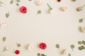 Flowers frame made of beige and red roses, eucalyptus leaf on pale pastel beige background. Flat lay, top view. Floral wreath frame background.