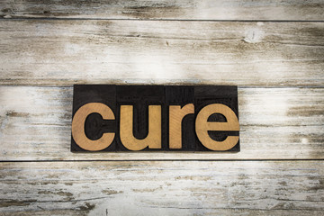 Cure Letterpress Word on Wooden Background