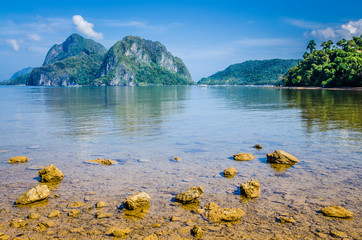 Stony beach during low tide in front of huge rocks in Background, El Nido, Palawan, Philippines
