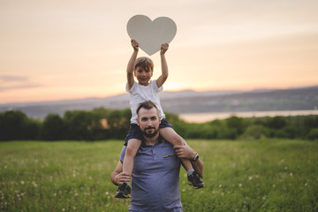 Fototapeta premium Young father walking with his young son in the meadow at the sunset