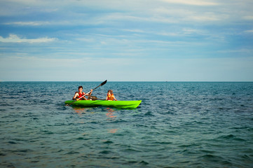 Fototapeta na wymiar Man and boy swims on kayak in the sea on background of island. Kayaking concept