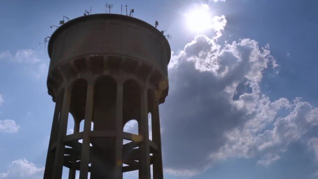 Northcliff JHB - Left side close up placement - Looking up at a large concrete reservoir on stilts with arches the water tower against cloudy background with lens flare sun