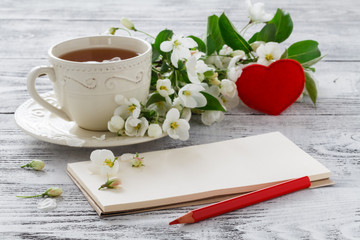 Cup of tea and pink sakura blossom on a old wooden background