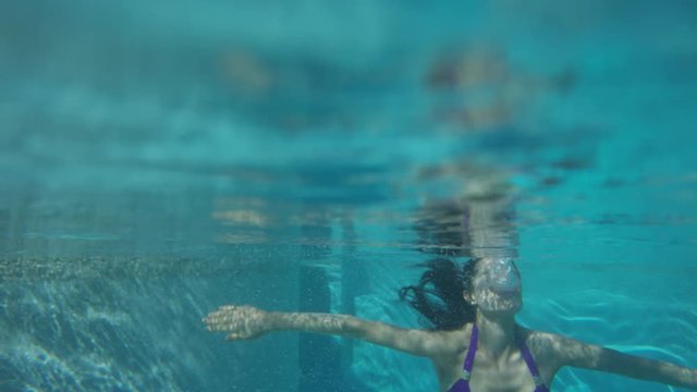 Medium slow motion shot of woman surfacing in pool. Cedar Hills, Utah, United States