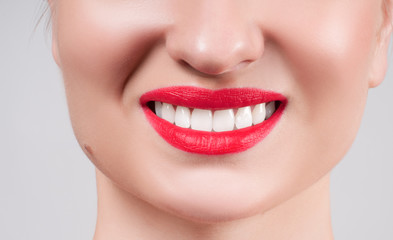 Fototapeta premium White teeth and red lips. Perfect female smile after whitening teeth.