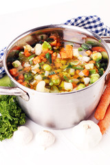 Broth with carrots, onions various fresh vegetables in a pot - c