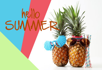 Honeymoon and Holiday concept.Couple of attractive pineapples in stylish sunglasses on colorful and hello summer word background