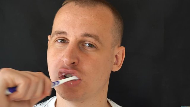 Man Cleans Teeth on black background.