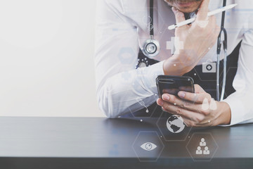 close up of smart medical doctor working with smart phone and stethoscope on dark wooden desk with virtual icon diagram