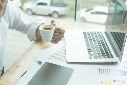 young graphic designer working with computer. creative man using digital tablet at modern office. businessman drink coffee in the morning. architect with color swatch sample catalog. 