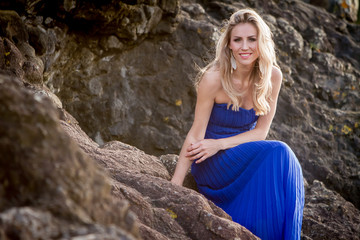 outdoor portrait of young beautiful woman in blue gown posing on natural background