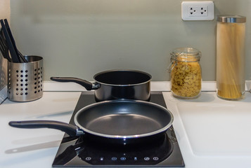 Black pan on Induction stove top panel in modern kitchen for cooking, closeup