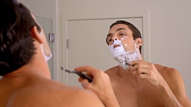 Athletic man shaving in the morning.