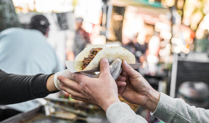 Chef handing a taco to a foodie at a street food market