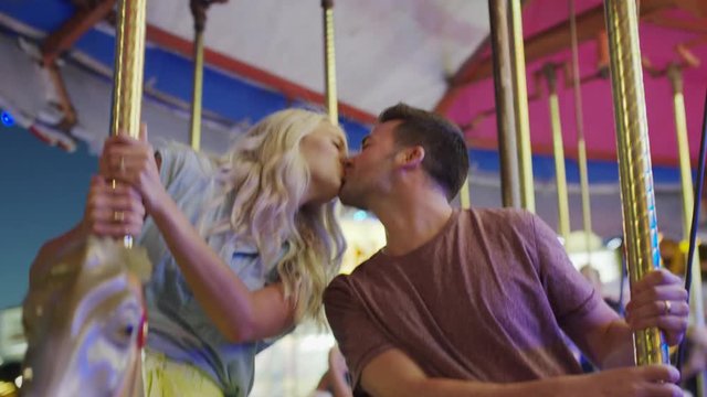 Medium low angle shot of couple kissing on carousel. Pleasant Grove, Utah, United States