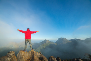 Obraz premium Man on top of mountain sitting on the rock watching a view landscape at Doi Luang Chiang Dao, ChiangMai Thailand