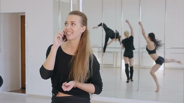 Young woman have a phone call during a pole dance class