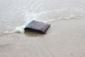 Fototapeta na wymiar Old Leather Wallet with drowning in beach copy space 
