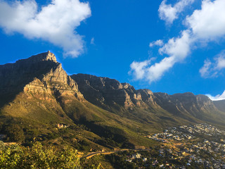 Fototapeta na wymiar Table Mountain national park view near city and the beach with clouds and blue sky background in Camps Bay, Cape Town, South Africa, foto from Lion's Head mountain