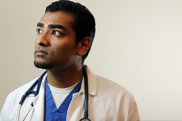 Young handsome doctor in blue scrubs looking up