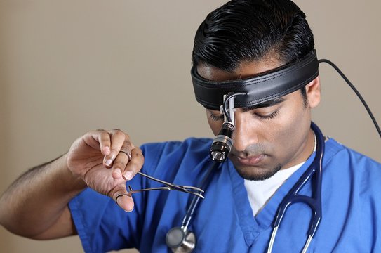 Young Handsome Doctor In Blue Scrubs And Headlight Holding Clamp