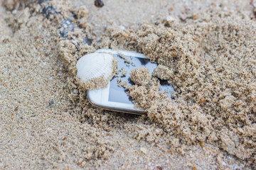 Mobile phone is in the sand at the beach, the sea.