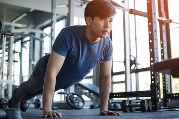 Young Asian man exercising in the fitness gym with flare light