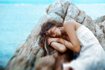 Naklejka premium beautiful young woman sleep on the rocks at the beach