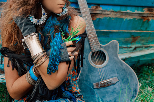 attractive gypsy girl close up portrait with a guitar leaning against the boat at background