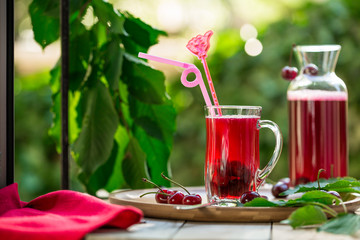 Homemade sour cherry compote in glass cup with jar on bamboo tray