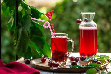 Homemade sour cherry compote in glass cup with jar on bamboo tray