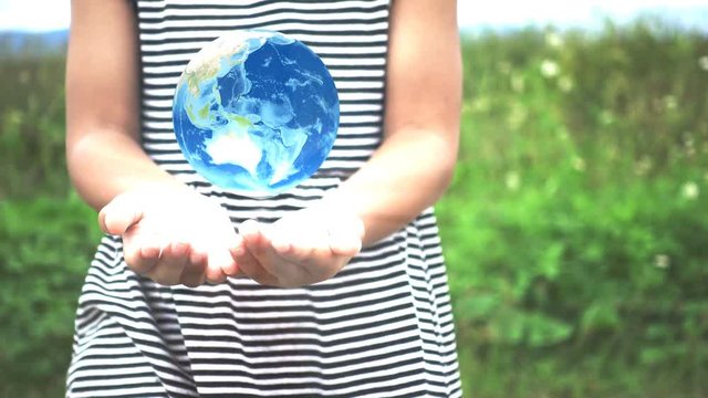 Asian little girl's hands holding spinning globe at outside. Elements of this image furnished by NASA